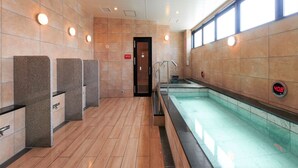 A modern indoor swimming pool area with a wooden floor, a changing room with benches, and a digital clock displaying 40.8. - CABIN & HOTEL ReTIME - Hostel (Naha)