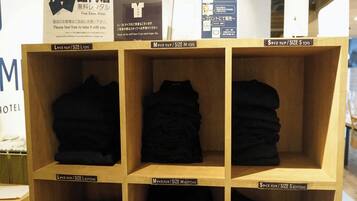 A hotel room with wooden shelves displaying folded clothes in sizes L, M, and S.