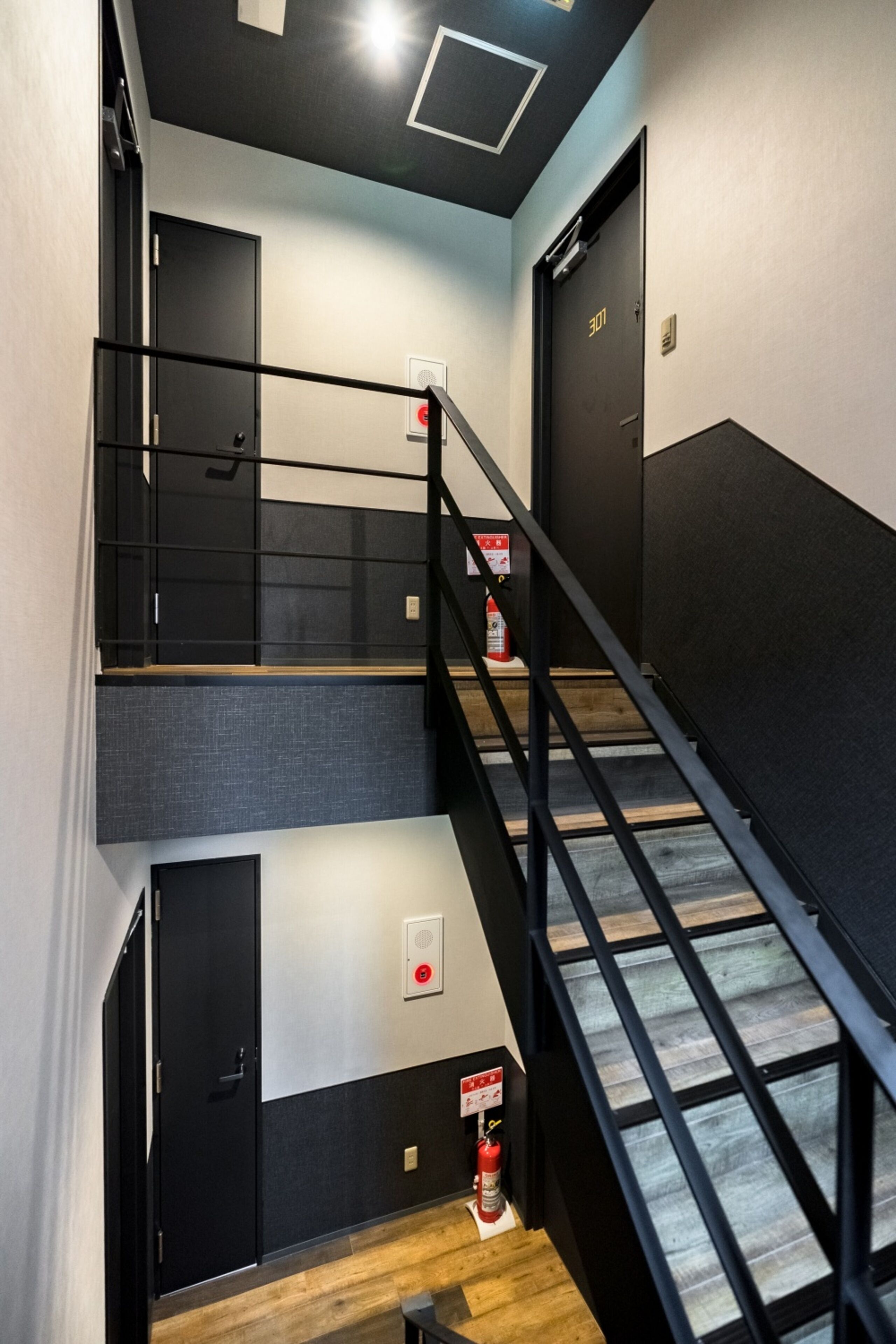 A modern staircase with black railings, a fire extinguisher, and a door marked "307".