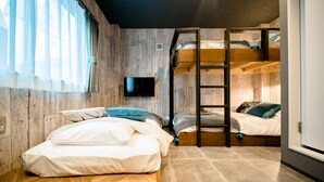 A room with a bunk bed, a flat bed, and a TV mounted on the wall. - IKIDANE Residential Hotel Komagome (Tokyo)