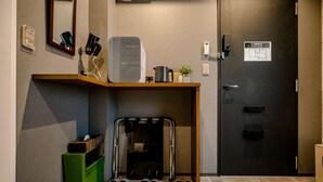 A hotel entrance with a reception desk, a coat rack, a trash bin, and a door with a sign. - IKIDANE Residential Hotel Komagome (Tokyo)