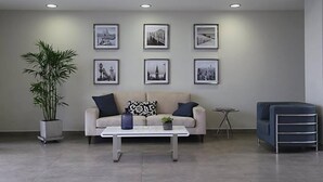 A modern living room with a sofa, a coffee table, and a blue armchair. There are six framed pictures on the wall and a potted plant. - FLAT 1D (entre aeropuerto y Miraflores) (San Miguel)
