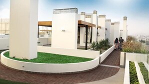 A rooftop terrace with a circular grassy area, white pillars, and a clear view of the city skyline. - FLAT 1D (entre aeropuerto y Miraflores) (San Miguel)