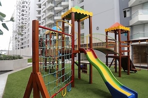 Kids can play safely in the enclosed outdoor play area with a slide, climbing structures, and a playhouse.