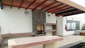Eine Außenpatio mit Kamin aus Stein, einer langen Bank und einer Pergola.