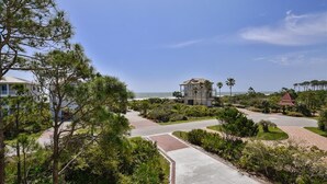 A coastal property with a paved driveway leading to a house, surrounded by lush greenery and palm trees. - A MEMORY OF A LIFETIME is what you will have when you stay at this beautiful Plantation home (St. George Island)