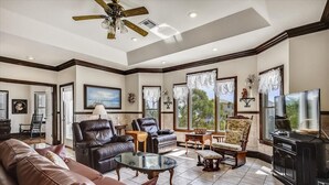 A spacious living room with leather sofas, a glass coffee table, and a ceiling fan. - A MEMORY OF A LIFETIME is what you will have when you stay at this beautiful Plantation home (St. George Island)