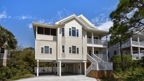 A two-story building with a balcony on the upper floor, a covered entrance, and a wooden fence in front. - A MEMORY OF A LIFETIME is what you will have when you stay at this beautiful Plantation home (St. George Island)