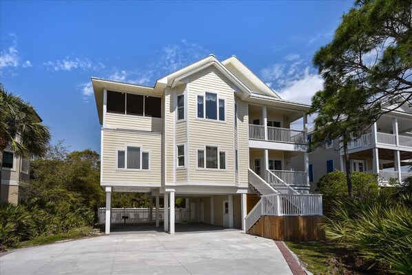 A two-story building with a balcony on the upper floor, a covered entrance, and a wooden fence in front. - A MEMORY OF A LIFETIME is what you will have when you stay at this beautiful Plantation home (St. George Island)