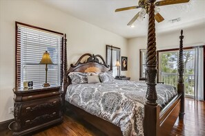 A bedroom with a large bed, a wooden dresser, a nightstand, a lamp, and a ceiling fan. - A MEMORY OF A LIFETIME is what you will have when you stay at this beautiful Plantation home (St. George Island)