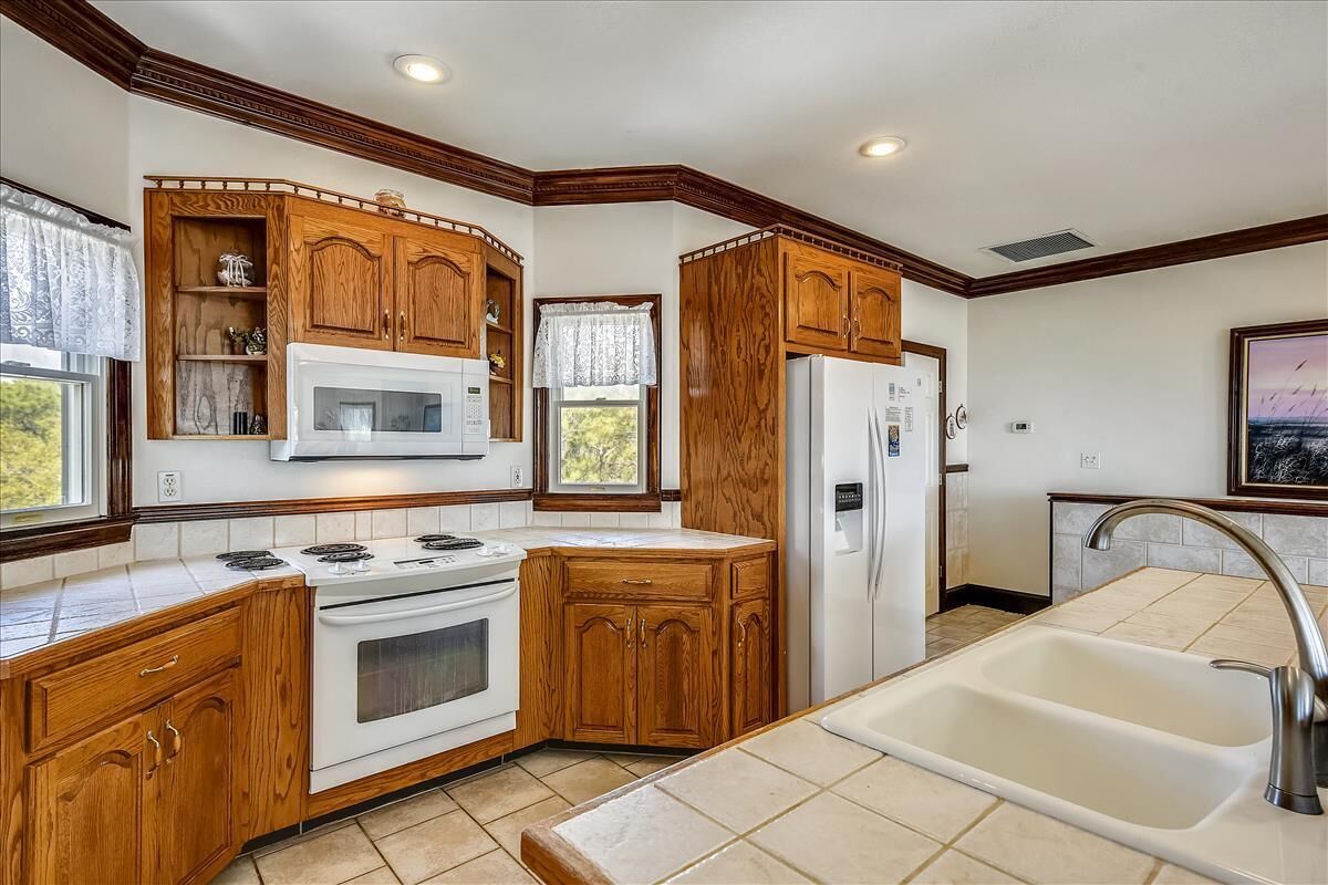 A kitchen with wooden cabinets, a white stove, a microwave, and a refrigerator.