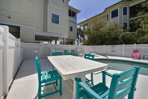 A pool area with a white table and turquoise chairs, surrounded by a white picket fence. - A MEMORY OF A LIFETIME is what you will have when you stay at this beautiful Plantation home (St. George Island)
