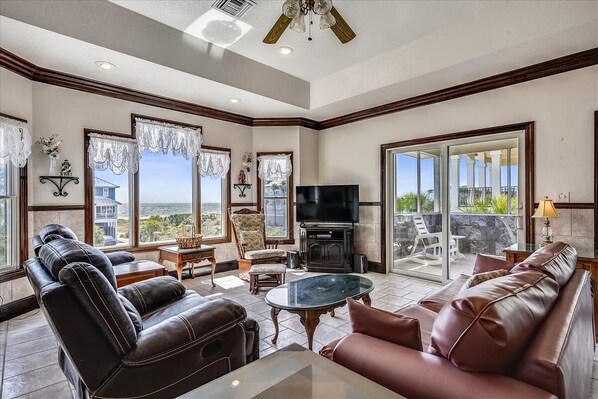 A spacious living room with leather sofas, a glass coffee table, and a flat-screen TV.