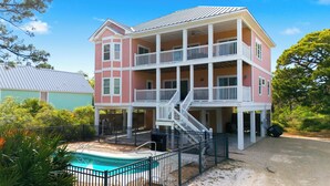 A multi-story house with a pool, balconies, and a staircase leading to the upper floors.