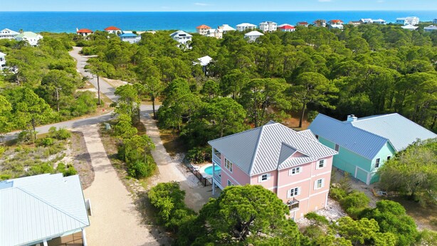 A coastal residential area with multiple houses, a clear road, and a swimming pool.