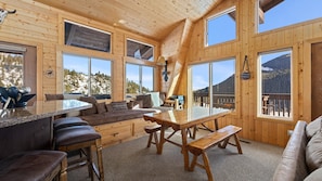 Enjoy expansive views of the surrounding landscape from the large windows of this cabin, featuring a comfortable seating area and dining space.