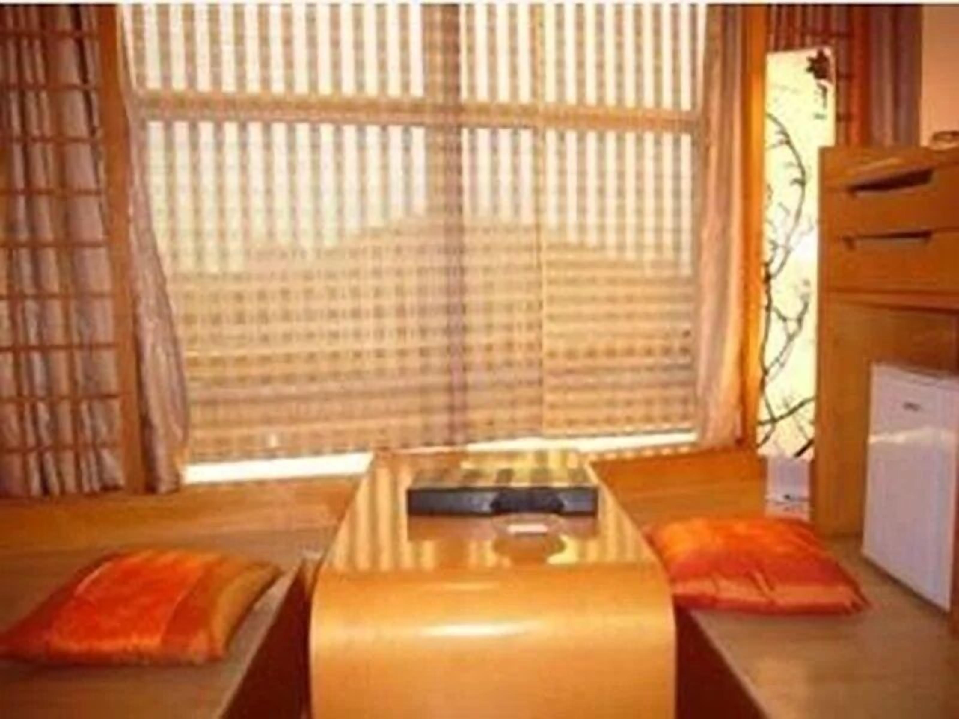 A room with a bed, a small table, and a window with curtains.