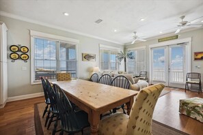 A dining area with a wooden table and chairs, a sofa, and a ceiling fan.