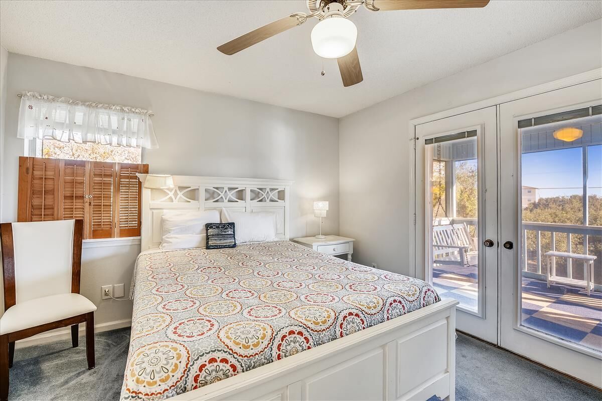 A bedroom with a bed, a chair, a nightstand, and a ceiling fan.