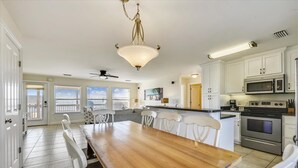 Un'ampia cucina con mobili bianchi, un tavolo da pranzo in legno e una ventola a soffitto.
