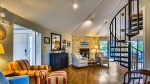 A spacious living room with a fireplace, a staircase, and a view of the outdoors. - BIRD WATCHER IS PARADISE FOR A NATURE LOVER!! (St. George Island)