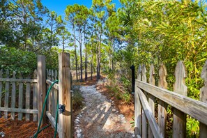 A wooden pathway flanked by a wooden fence, leading through a forested area with pine trees. - BIRD WATCHER IS PARADISE FOR A NATURE LOVER!! (St. George Island)
