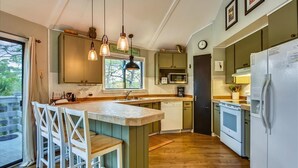 A kitchen with a central island, bar stools, a microwave, a dishwasher, and a refrigerator. - BIRD WATCHER IS PARADISE FOR A NATURE LOVER!! (St. George Island)