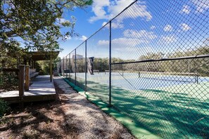 A fenced tennis court with a wooden deck and a covered seating area. - BIRD WATCHER IS PARADISE FOR A NATURE LOVER!! (St. George Island)