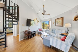 A spacious living room with a wooden floor, a sofa set, a television, and a ceiling fan. - BIRD WATCHER IS PARADISE FOR A NATURE LOVER!! (St. George Island)