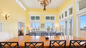 A dining room with a large wooden table, chairs, and a chandelier. - THIS FABULOUS FIRST-TIER PLANTATION property is the ultimate family gathering place! (St. George Island)