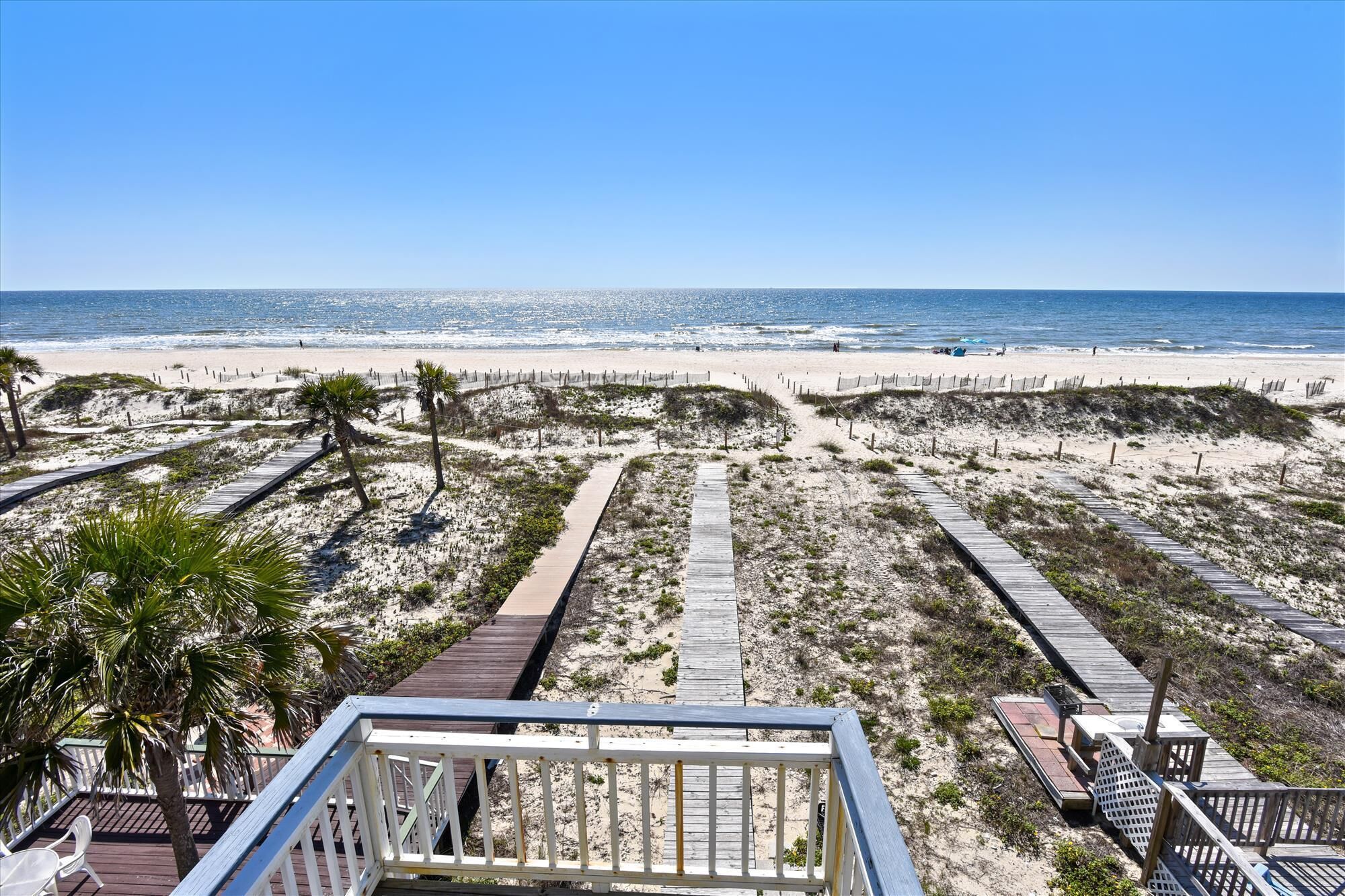 A beach with wooden walkways and palm trees.