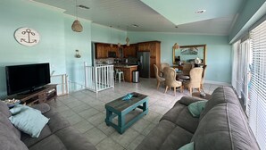 Ein Wohnzimmer mit einer Couch, einem Couchtisch, einem Fernseher und einem Essbereich mit Stühlen und einem Tisch.