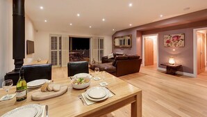 Un coin repas avec une table en bois dressée pour le repas, une cheminée et un salon comprenant un canapé et un tableau.