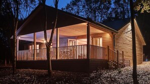 Une cabane en bois dotée d’un porche abrité et de grandes fenêtres.