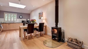 Une cuisine moderne avec des meubles en bois, une table à manger, des chaises et un poêle à bois.