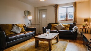 Ein gemütliches Wohnzimmer mit zwei Ledersofas, einem Holztisch und einer Stehlampe.