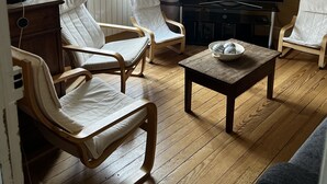 A living room with a wooden floor, a flat-screen TV, and two white cushioned chairs.