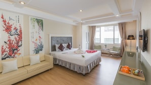 A hotel room with a bed, a sofa, a desk with a lamp, and artwork on the walls. - Dyn Opera Hotel (Ho Chi Minh City)