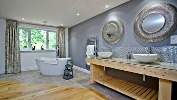 A modern bathroom with a freestanding bathtub, two sinks, and decorative mirrors.