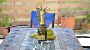 A bottle of wine on a tiled table with a glass and bananas in the background.