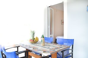 Una mesa de comedor con cubierta de baldosas, un cuenco de fruta y una botella.