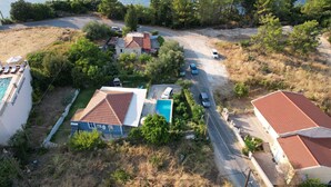 A coastal property with multiple buildings, a swimming pool, and a road leading to the sea.