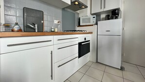 Ett modernt kök med vita skåp, en mikrovågsugn, en spis och ett kylskåp.