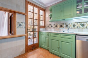 A kitchen with green cabinets, a window with a view, and a dishwasher.