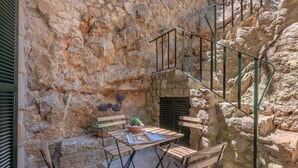 Pared de piedra con una escalera de caracol, muebles de madera y una planta en maceta.