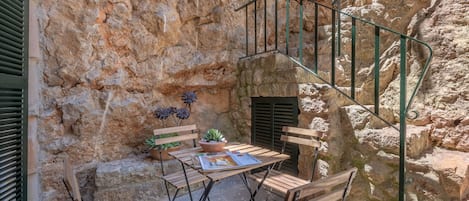 Pared de piedra con una escalera de caracol, muebles de madera y una planta en maceta.