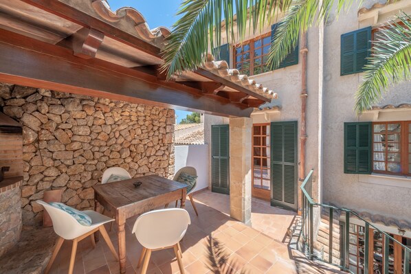 A patio with a stone wall, wooden table, and chairs.