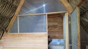 A small, wooden room with a sloped ceiling and a single bed. - Santuario Zona Lacandona (Ocosingo)