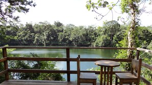 A wooden deck with a table and two chairs overlooking a lake surrounded by dense forest. - Santuario Zona Lacandona (Ocosingo)