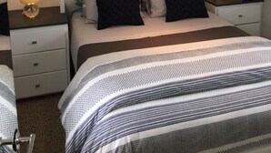 Un dormitorio con una cama grande, dos mesitas de noche con lámparas, un armario y un espejo.